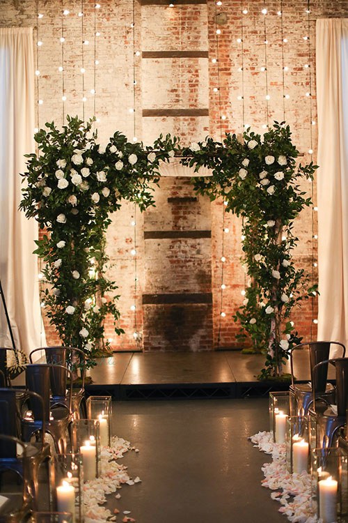 Rustic washed brick wall with green and white arch and lovely string lights and candles on the aisle. // ❤ Check Out These Gorgeous 20 Indoor Wedding Ceremony Ideas. // http://mysweetengagement.com/indoor-wedding-ceremony-ideas
