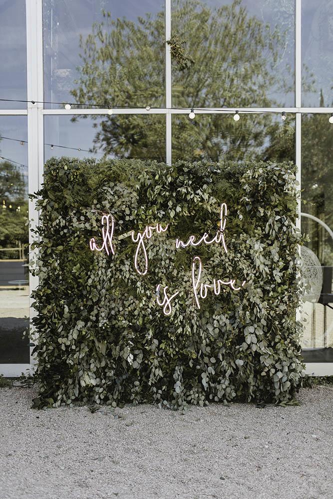 "All you need is love" neon lettering sign on greenery backdrop // Fun and bright neon wedding sign decor ideas // mysweetengagement.com