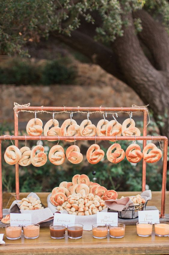 Industrial chic copper pipe pretzel hanging display with assorted dipping sauces. See More Trendy and Creative Ideas to Serve Pretzel on Your Wedding. | My Sweet Engagement