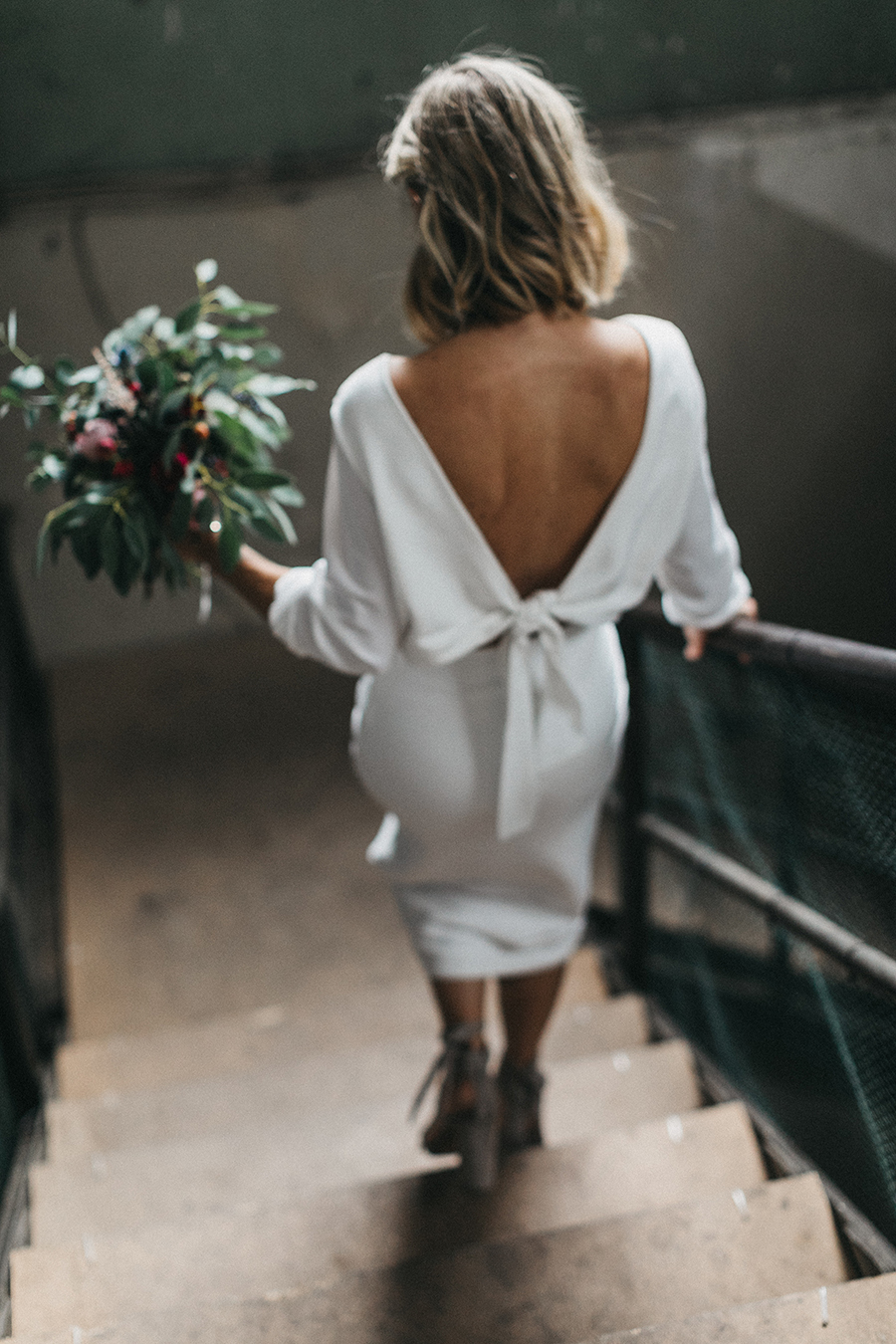 This mid length white dress with long sleeves and cut back is the perfect option for a stylish bride. // See more: 20 Stunning Civil Wedding Outfit Ideas to Make it Official In Style. // mysweetengagement.com
