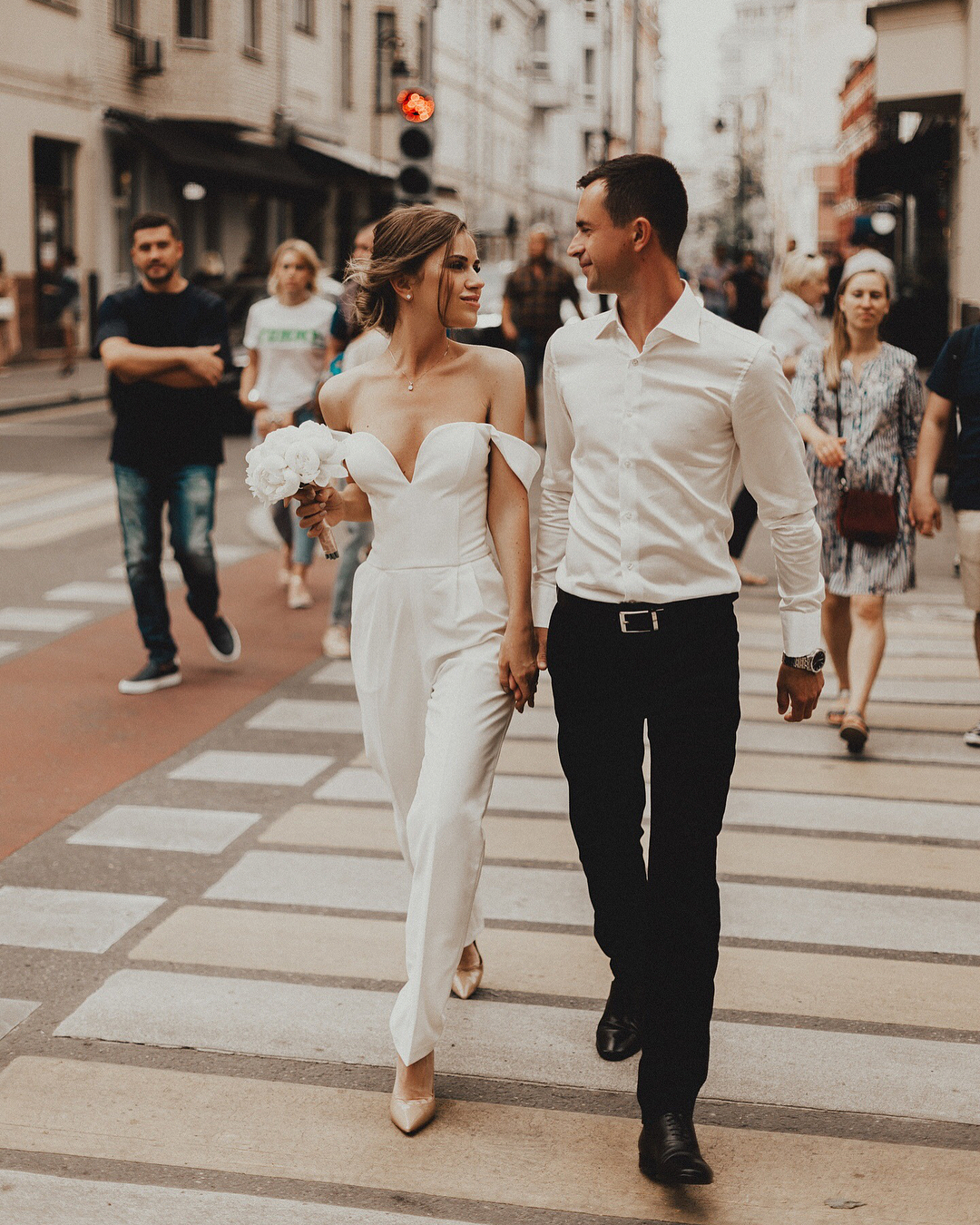 Modern bride look for a courthouse wedding celebration. Off-the-shoulder jumpsuit and all white flowers small bouquet. // See more: 20 Stunning Civil Wedding Outfit Ideas to Make it Official In Style. // mysweetengagement.com