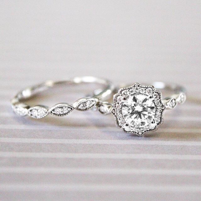 vintage platinum halo engagement ring with round shaped center stone paired with intricate wedding band
