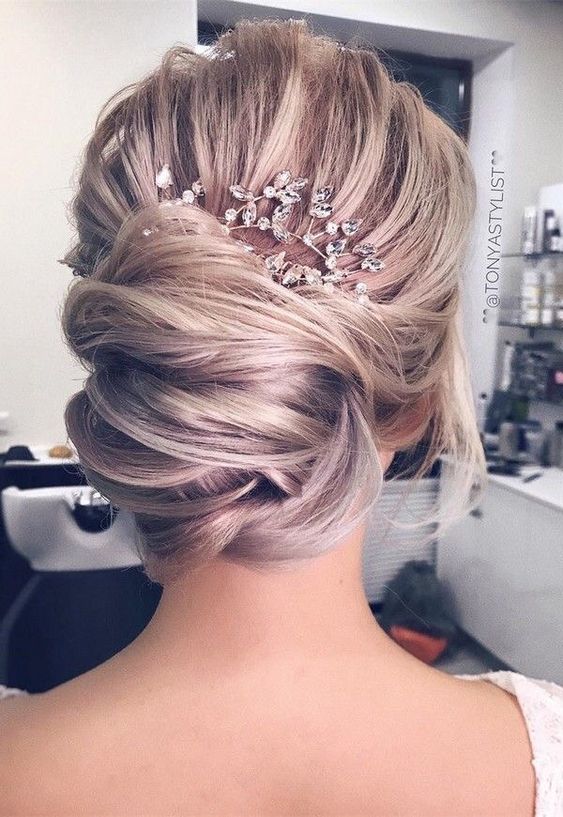 Polished wedding hairstyle idea: hair bun embellished with a hairpiece, perfect for classic brides.