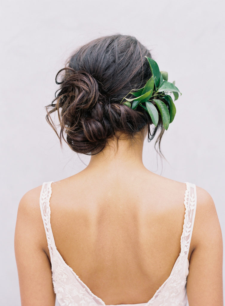 Romantic Bridal Updo with twisted side swept bridal updo with greenery embellishments.