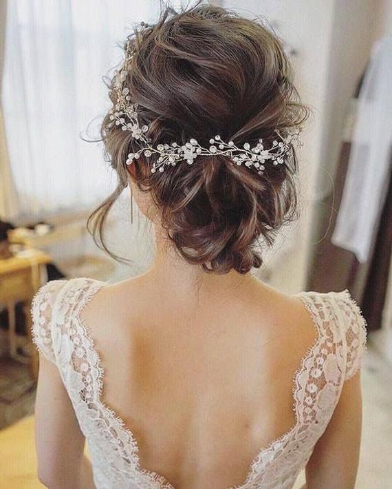 Textured messy bun embellished with a delicate wreath hairpiece.