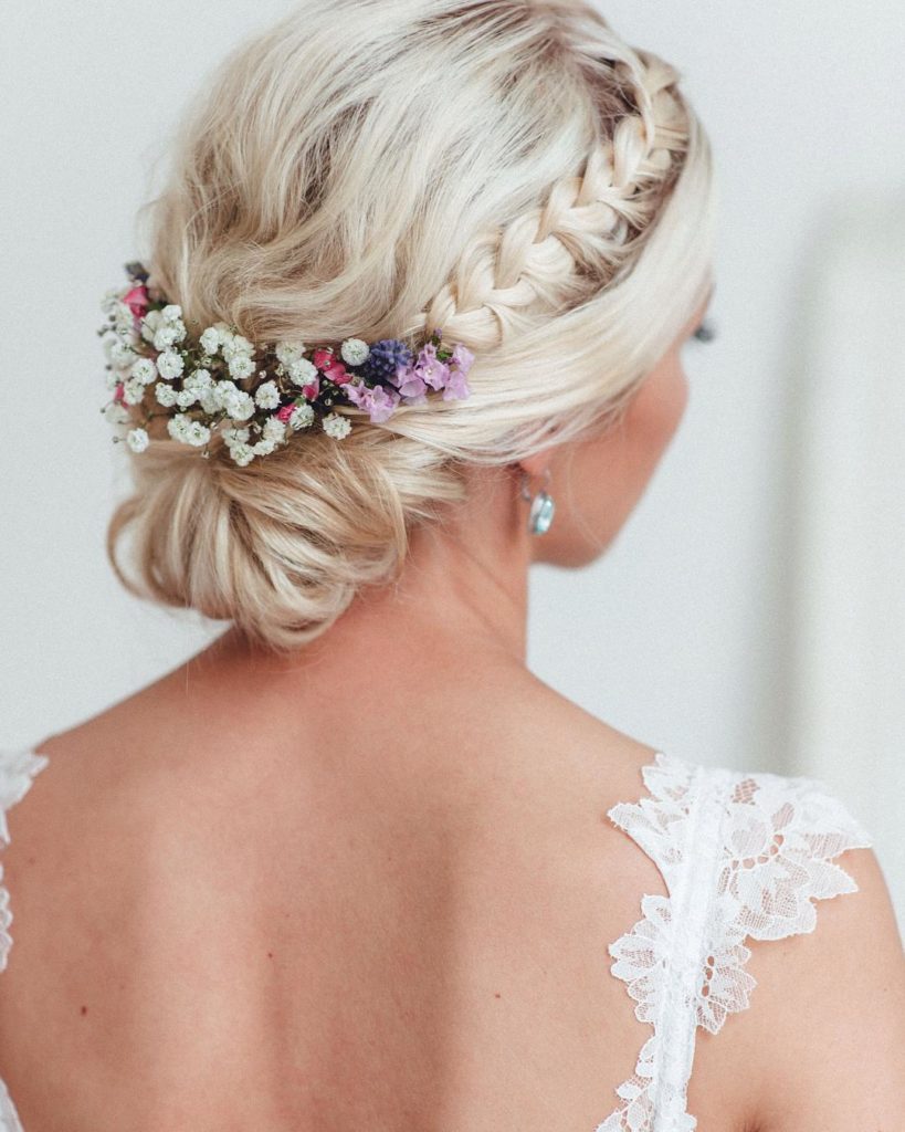Graceful braided low hair bun embellished with baby's breath flowers. Perfect hairstyle for a day time wedding.