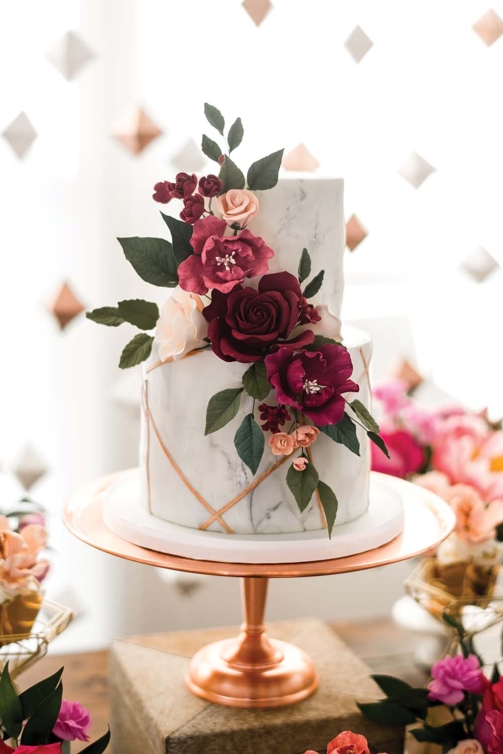Marble themed wedding ideas: two tiered marble cake with geometric gold accents and bold burgundy flowers. // mysweetengagement.com