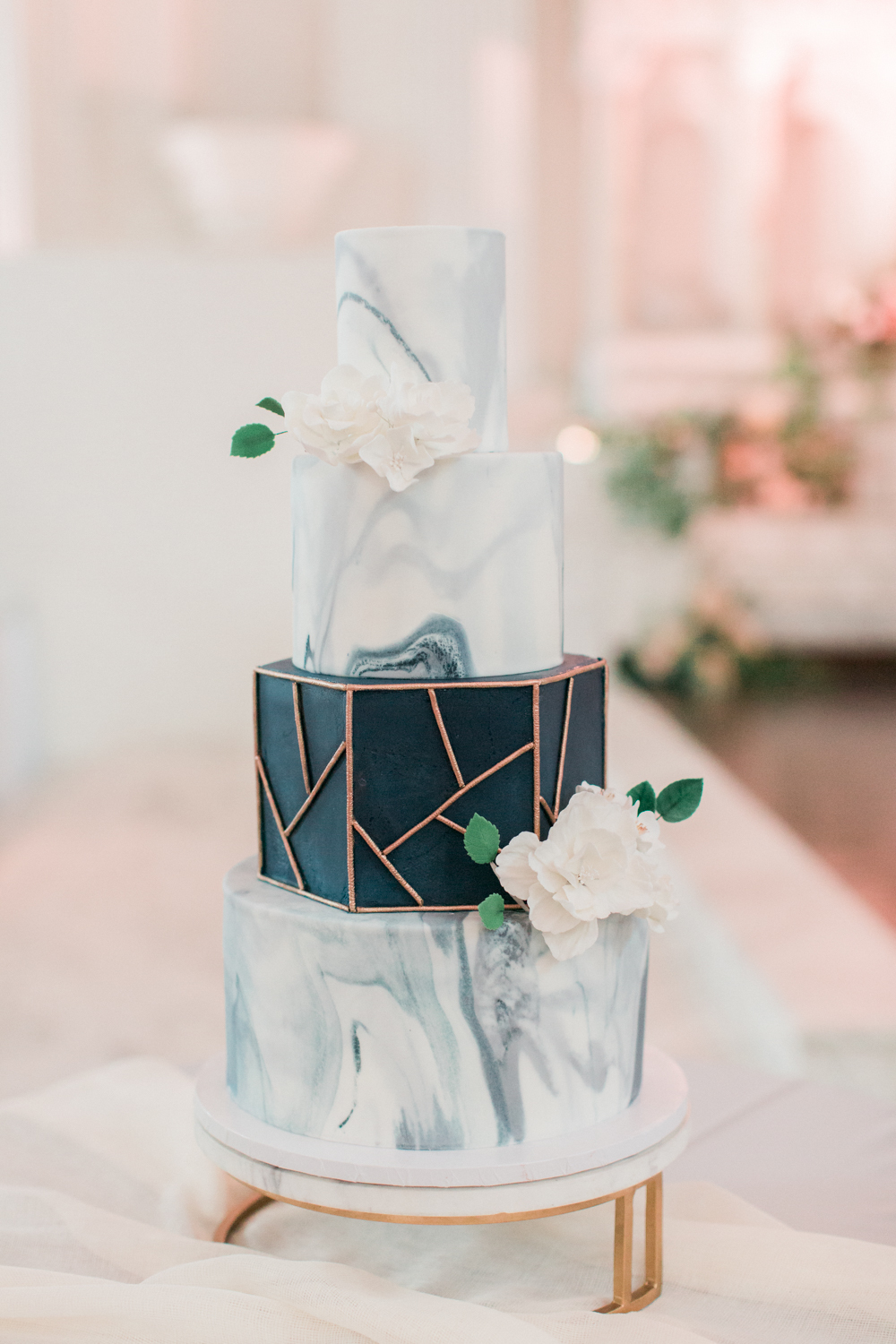 Marble themed wedding ideas: modern four tiered wedding cake with black and gold geometric accents and delicate white flowers. // mysweetengagement.com
