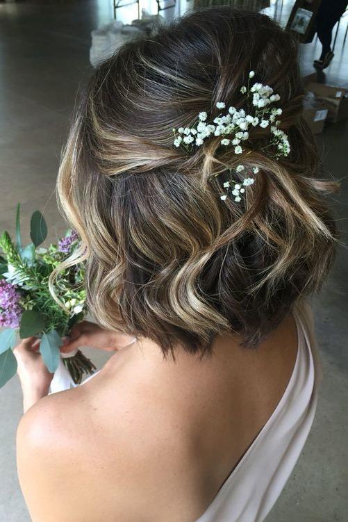 Short length wavy half up half down hair idea with delicate floral embellishment. // Gorgeous half up half down bridal hairstyle ideas to impress on your wedding day. // mysweetengagement.com