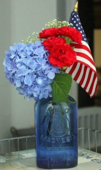 Red, White and Blue: Awesome and elegant Americana decorations for a 4th of July theme bridal shower. // Repurpose blue glass bottles for an unexpected patriotic floral arrangement. The American flag is the icing on the cake. // mysweetengagement.com