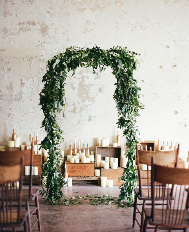 Wood boxes and gold candles create an unexpected backdrop for this indoor wedding ceremony. The greenery arch and wood chairs help to create a perfect whimsical ceremony setup. // ❤️ Check Out These Gorgeous 20 Indoor Wedding Ceremony Ideas. // https://mysweetengagement.com/indoor-wedding-ceremony-ideas