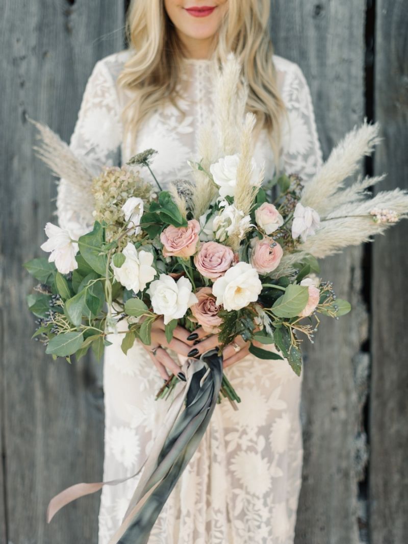 Long sleeve lace wedding dress and wedding bouquet with white and blush flowers, greeneries and pampas grass.