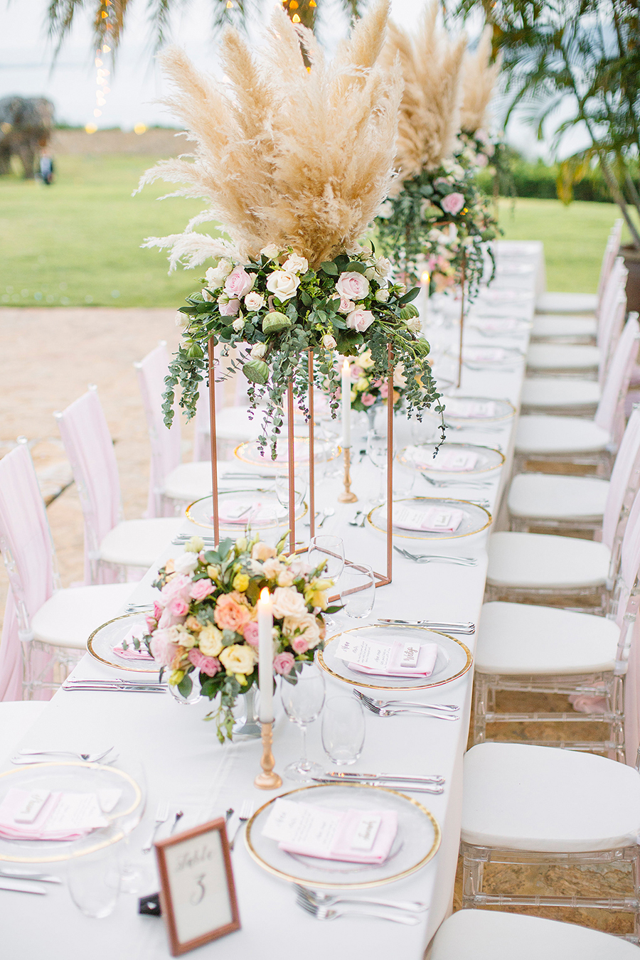 White wedding table with blush and copper accents and tall pampas grass and greeneries centerpiece