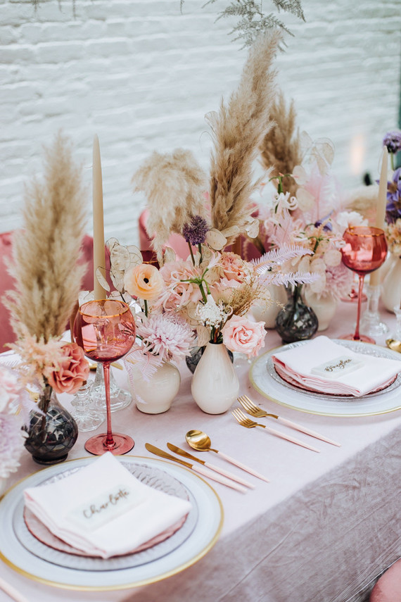 Blush pink wedding table decor with gold and white accents, with blush pink flowers and pampas grass as centerpieces.