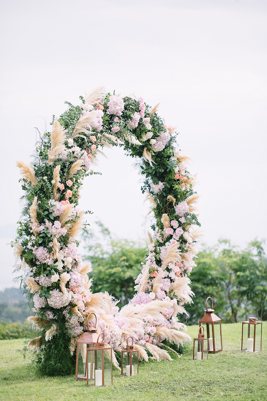 Circular wedding ceremony arch with blush flowers, greeneries and pampas grass.