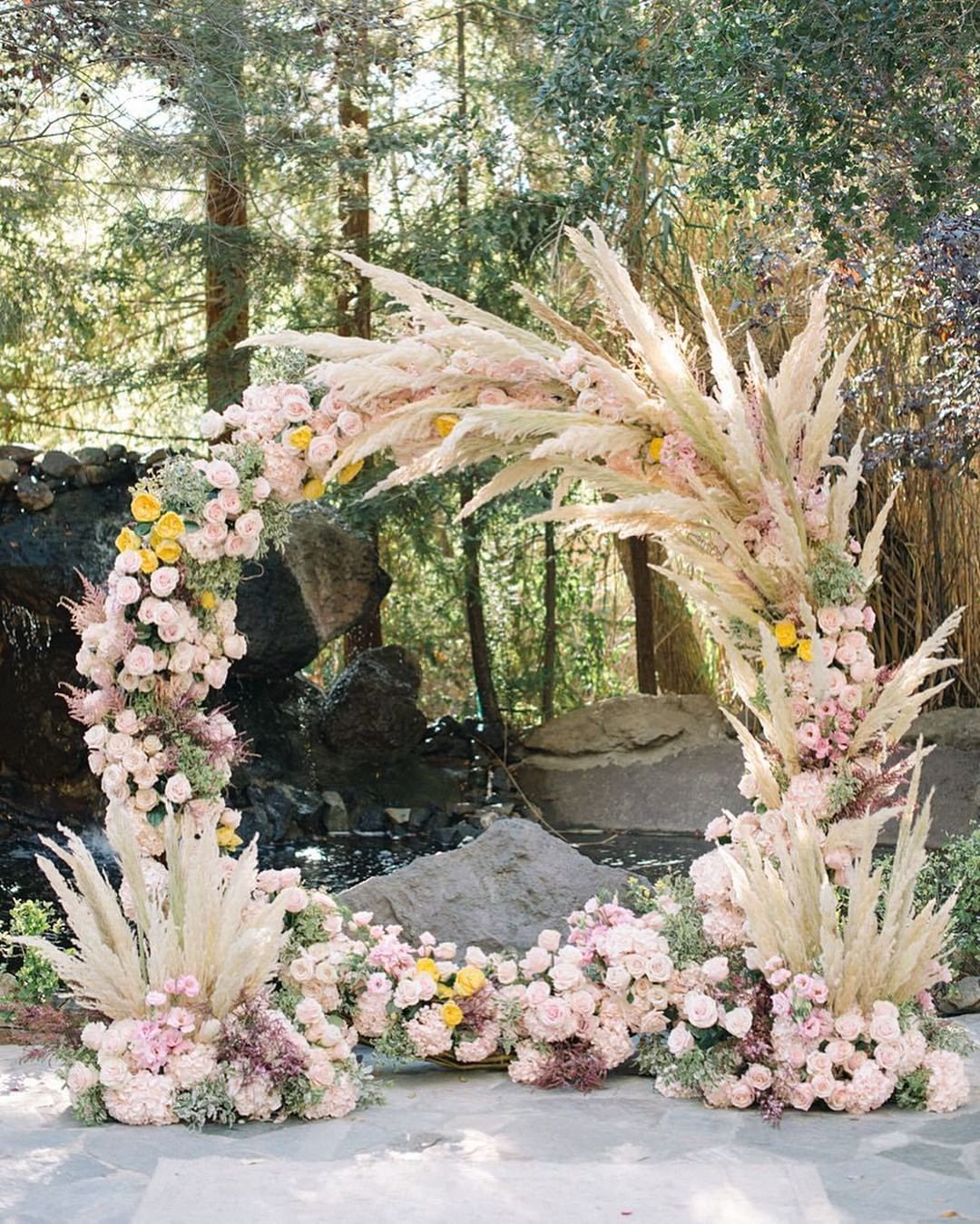 Circular wedding ceremony arch with blush flowers and pampas grass accents.