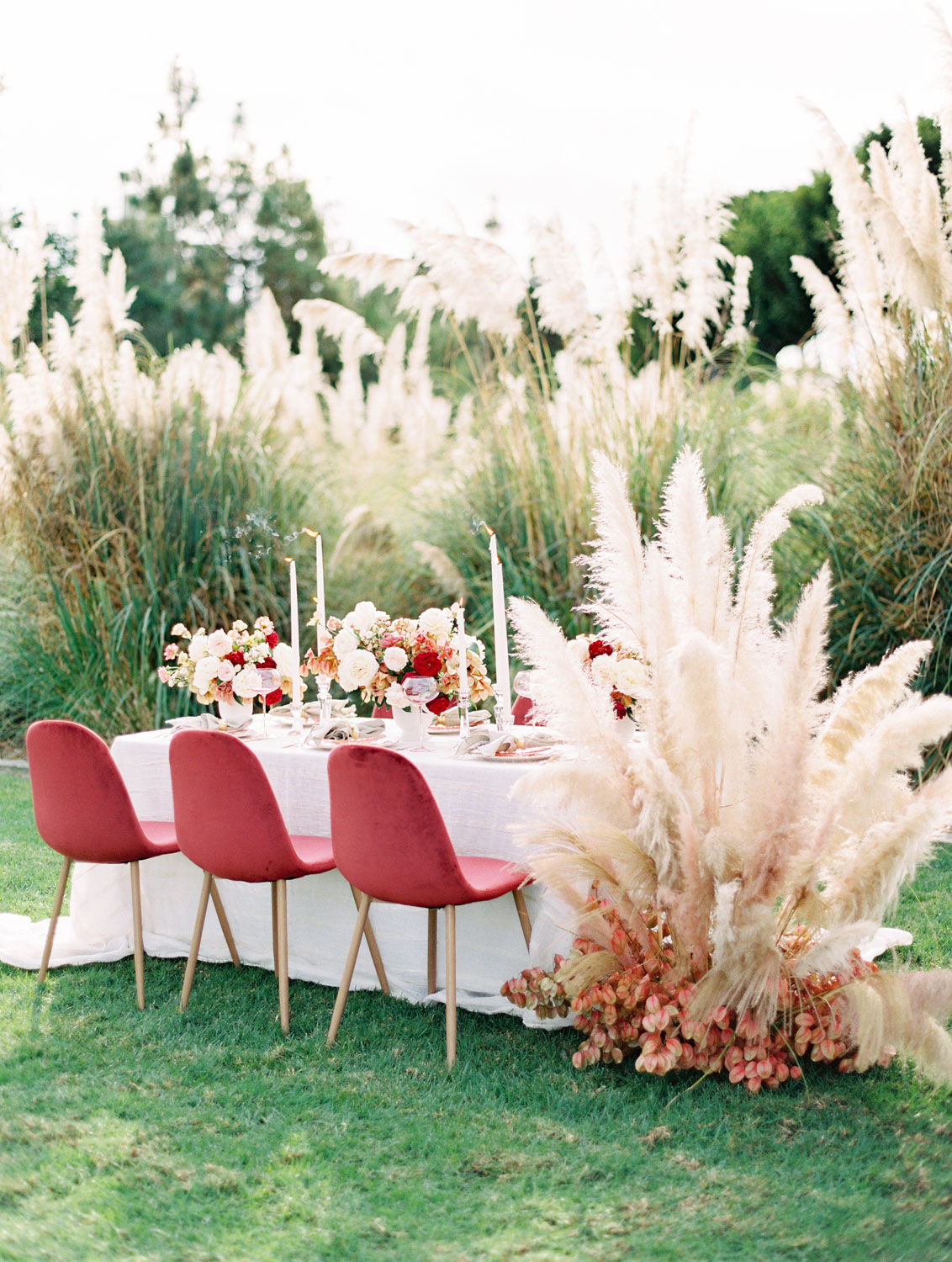 garden wedding reception table with white cloth, living coral chairs and big Cortaderia Selloana installations.