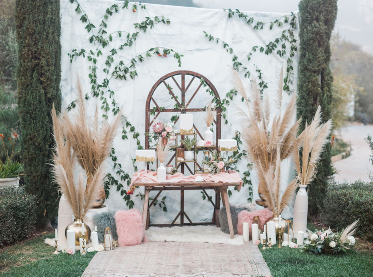 wedding backdrop decoration with tall pampas grass vases, blush and white accents and candles.