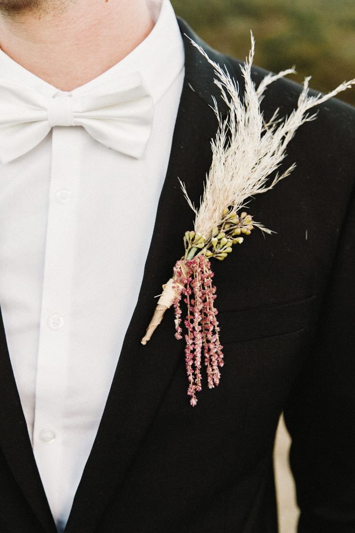 Groom outfit: white bow tie and shirt, black blazer with pampas grass boutonnière.