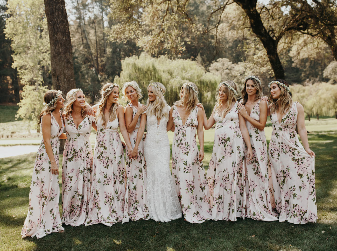 Bride and bridesmaid portrait. Bride wears a long lace dress and bridesmaids wear white dresses with blush flowers and floral crowns.