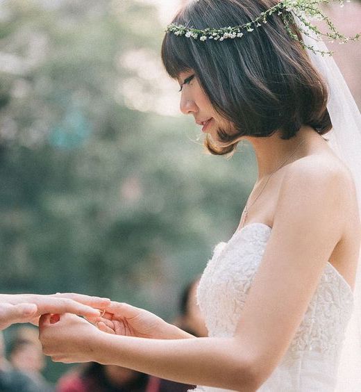 very short wedding hairstyle with bangs, styled down with delicate floral crown and veil