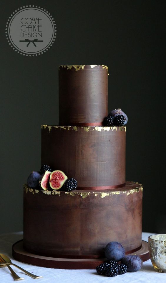 3 tiered chocolate wedding cake with gold edges, topped with blueberries and figs