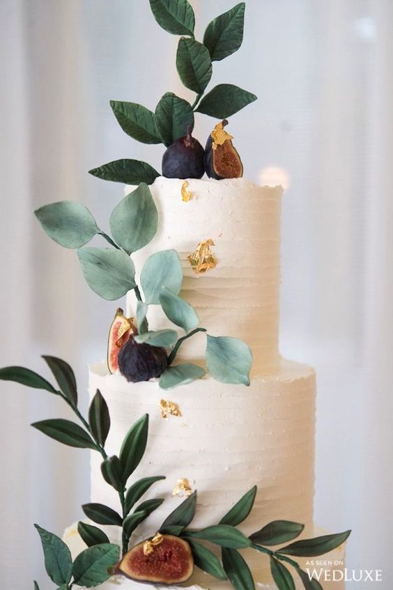 elegant white frosting wedding cake decorated with greeneries and figs