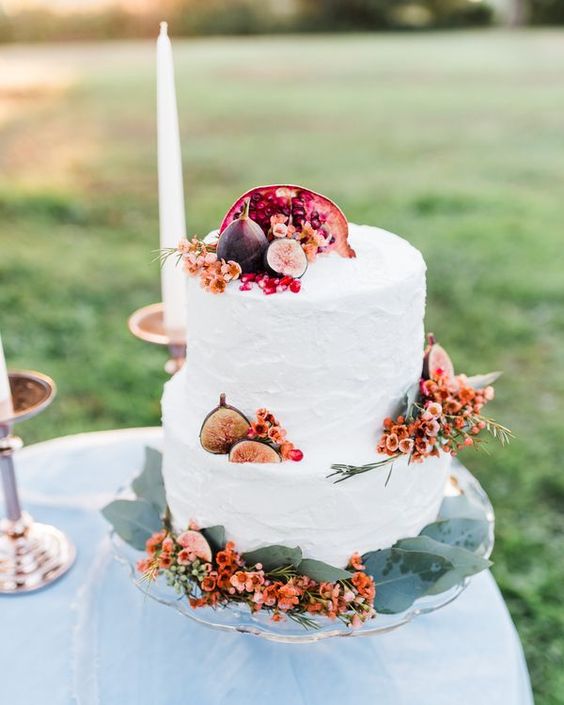 two tier, white frosting autumn wedding cake embellished with orange flowers and figs