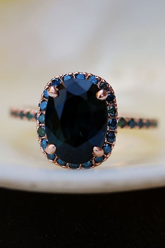 oval shaped sapphire engagement ring with blue diamonds halo in rose gold setting