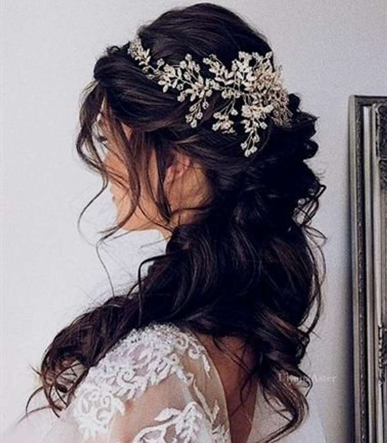 messy half up half down bridal hairstyle on dark hair with hairpiece accessory