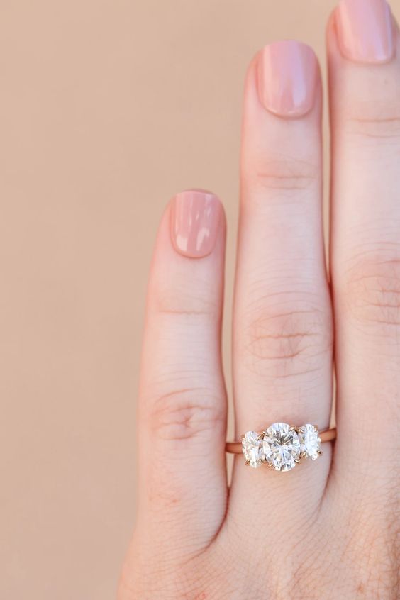 oval shaped three stone engagement ring on a rose gold band