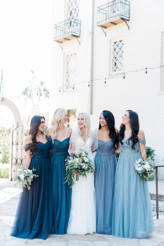 portrait with bride and bridesmaids wearing mismatched blue shades of dresses