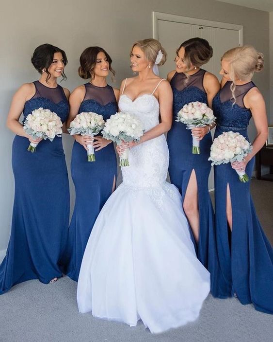 bride and bridesmaids portrait. bride wears sweetheart mermaid dress and bridesmaids wear matching navy blue dresses. both are wearing their hair up and holding blush bouquets