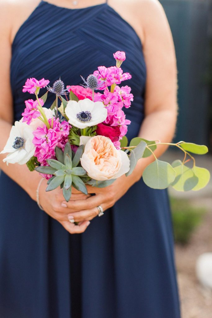 bridesmaid wearing Pantone Classic Blue dress holding a small bouquet with pink, white and peach flowers
