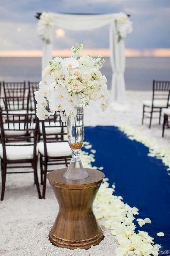 beach wedding ceremony with Pantone Classic Blue colored path and white flowers and drapery altar facing the ocean