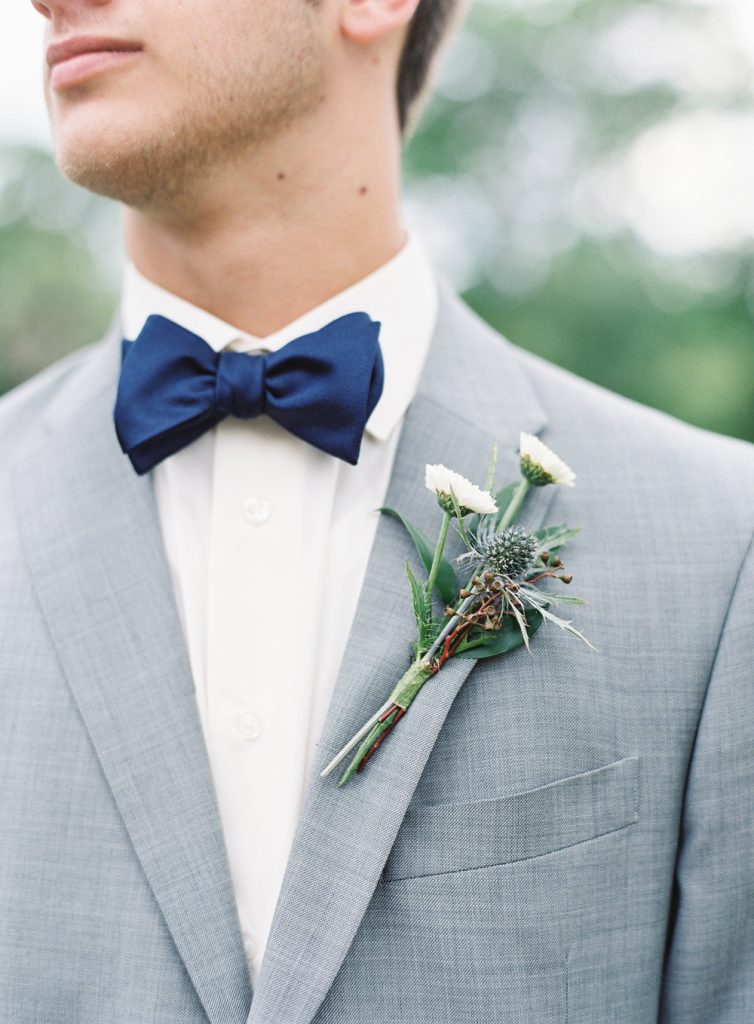 groom wearing gray suit, white shirt and navy blue bow tie