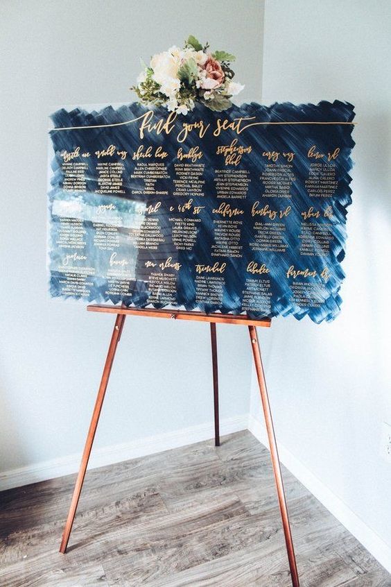wedding seating chart in acrylic material with blue background and gold calligraphy