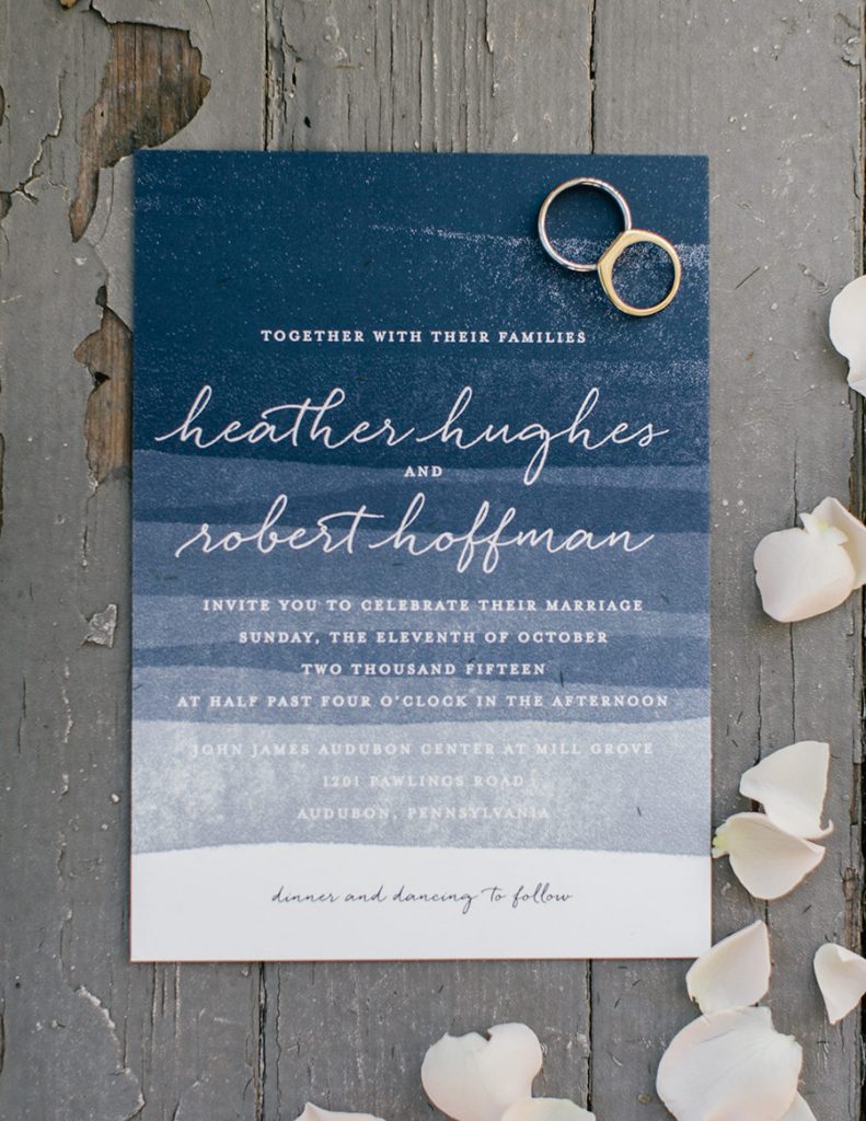 wedding invitation with shades of blue in watercolor and white details and wedding rings on top