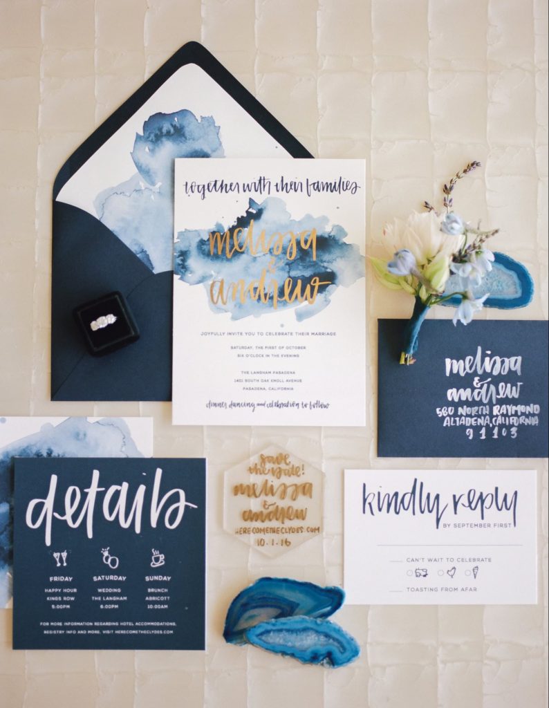 wedding stationery set on white paper, with classic blue watercolor details, hand written calligraphy and gold accents