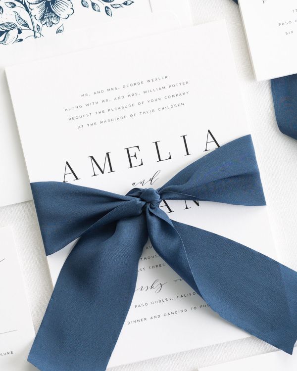 modern minimalist wedding invitation in white paper, with dark blue fonts and 2020 Pantone color of the year Classic Blue ribbon