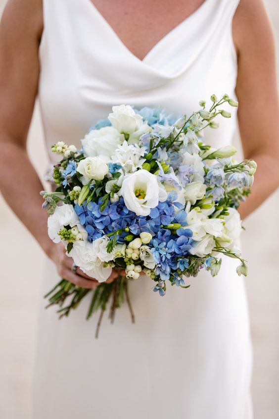 bride holding small wedding bouquet with white and blue flowers