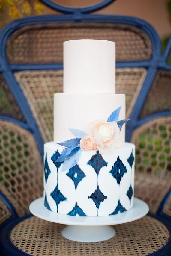 3 tiered modern wedding cake with white frosting and Pantone Classic Blue prints, embellished with peach flowers