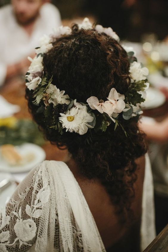 bride with natural curly hair wearing a low bun with a floral crown