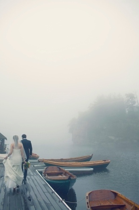 bride and groom walking on a dock with foggy skies