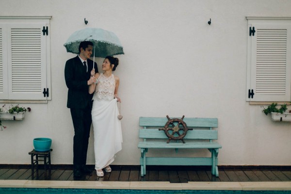 bride and groom holding an umbrella on a rainy day wedding