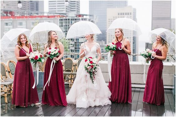 bride and bridesmaids holding matching clear umbrellas on a rainy day wedding