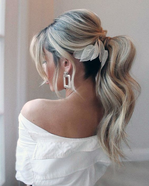 bridal hairstyle on blonde hair with ponytail and soft waves, puffy crown and delicate gold leaf hairpiece.