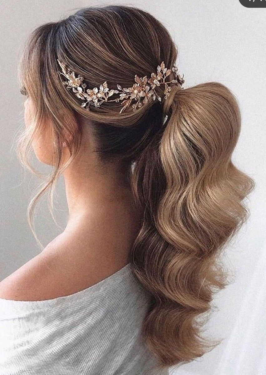 elegant bridal hairstyle with low ponytail and soft waves, adorned by a stunning gold hairpiece.
