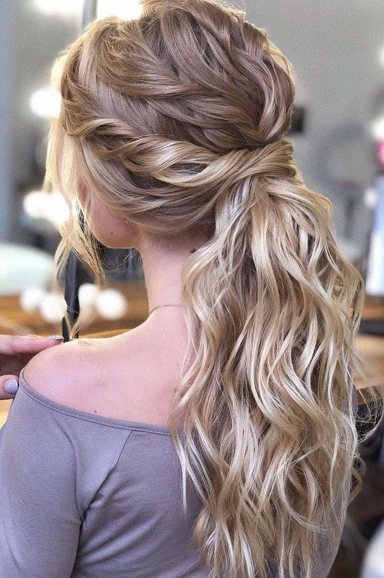 bridal hairstyle idea on blonde hair with ponytail, beach waves, twisted locks and loose hair strands around the face.