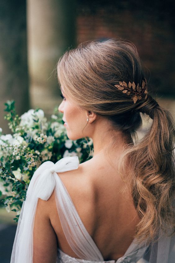 bride with a low ponytail hairstyle, soft waves and gold leaves hairpiece